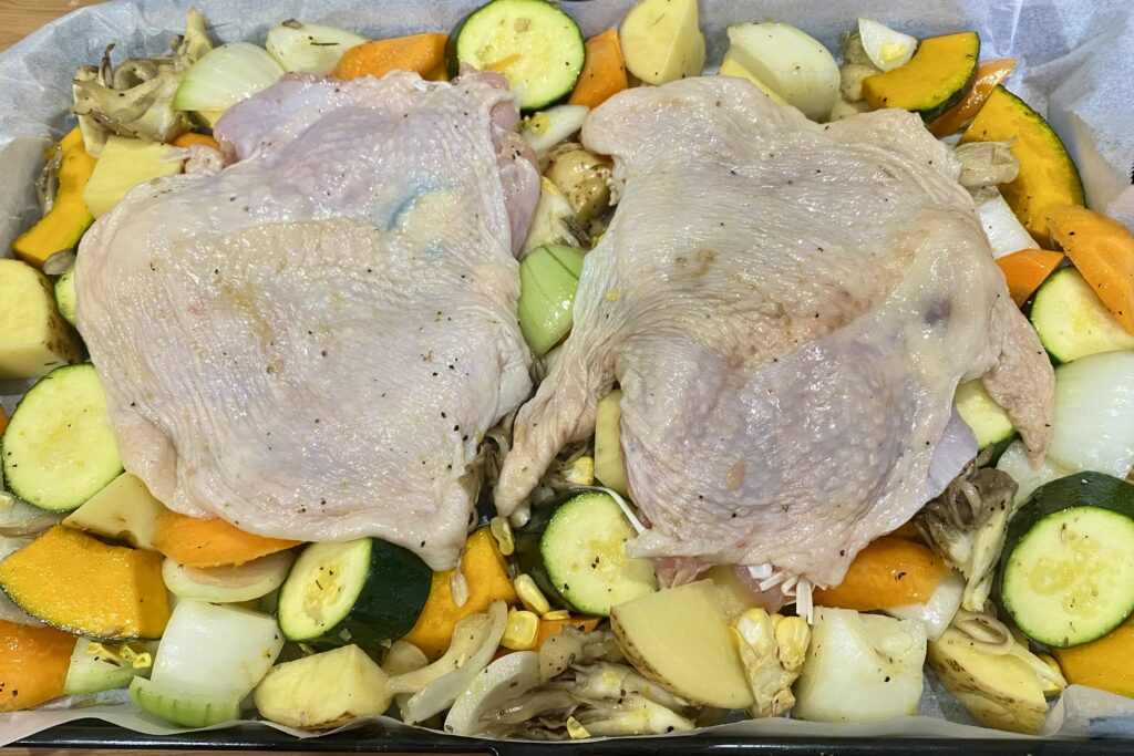野菜を並べた天板の上に鶏肉を乗せた様子